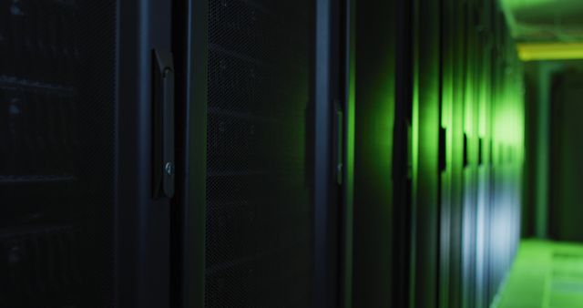 Modern data center featuring long aisle of dark server racks under dim green lighting. Suitable for illustrating concepts of data storage, backup solutions, cybersecurity, and cloud computing. Ideal for use in technology articles, IT company websites, and digital infrastructure promotions.