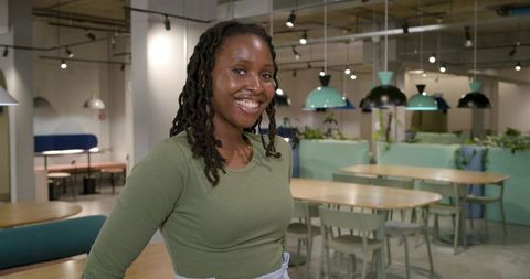 African american woman smiling in modern coworking cafe with pastel teal interior