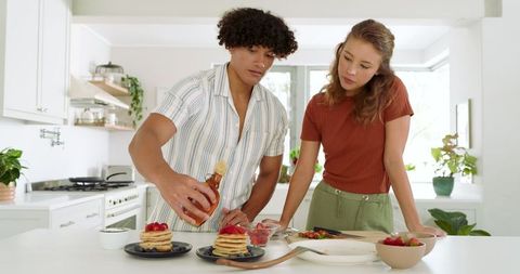 Couple Making Breakfast Pancakes with Strawberries in Modern Kitchen
