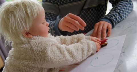 Father teaching daughter to draw at home, creative learning moment