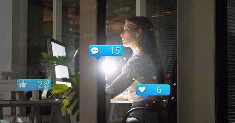 Woman Working Late Reviewing Social Media Notifications in Modern Office