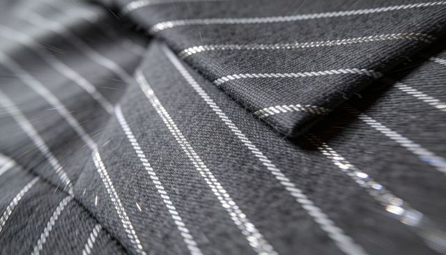 Closeup showing black pinstripe suit lapel with metallic thread highlight and twill texture