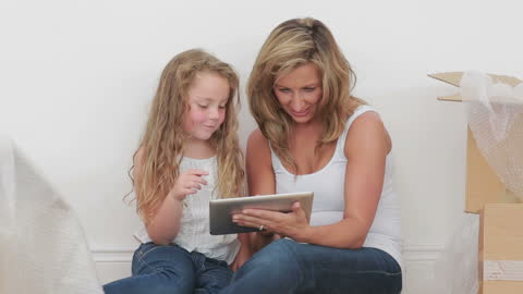 Mother and Daughter Sitting on Floor Using Tablet Together