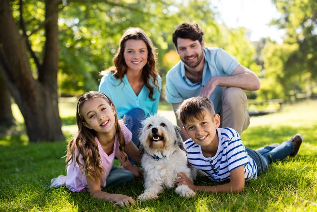 Family enjoying quality time outdoors in a park on a sunny day. Parents and children smiling and bonding with their dog on the grass. Ideal for use in advertisements, family-oriented content, lifestyle blogs, and promotional materials for outdoor activities.