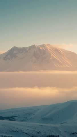Sun Climbing Eastern Sky Casting Warm Light on Snow-Covered Peak over Drifting Fog | Vertical Video