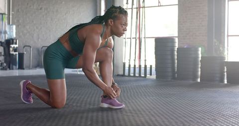 Woman Tying Shoe Laces in Gym Preparing for Fitness Routine