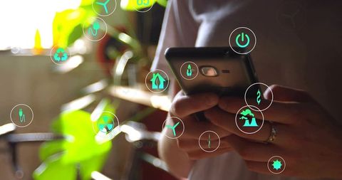 Adult woman holding smartphone tapping green eco icons at home with sunlit plants