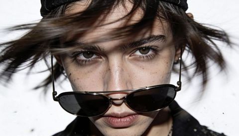 Windblown closeup of woman wearing sunglasses with intense gaze and freckles edgy fashion