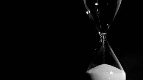 Hourglass with Falling Sand against Dark Background