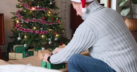 Man wrapping gifts in festive christmas setting