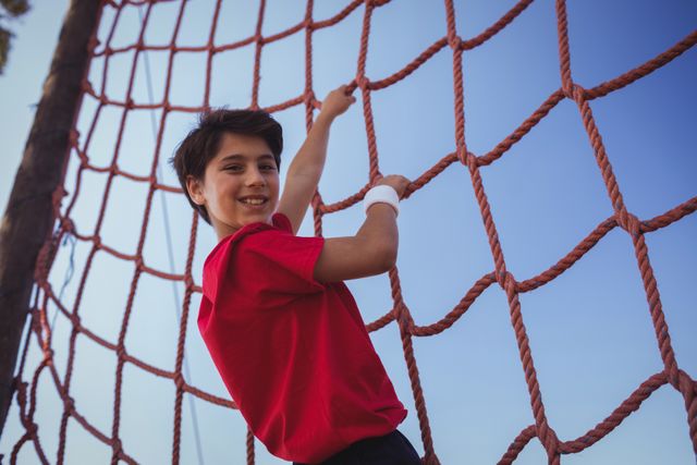 Boy climbing a net during obstacle course training in the boot camp