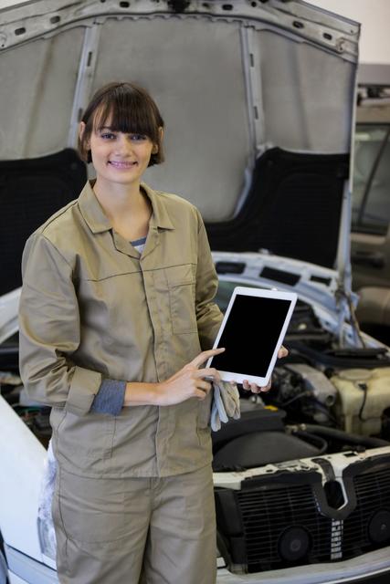 Smiling female mechanic using digital tablet at the repair garage