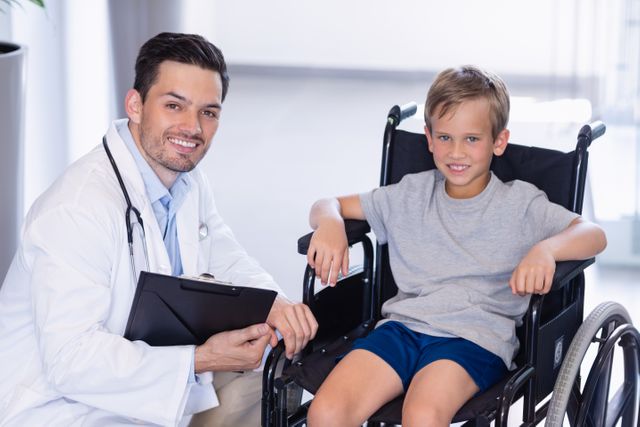 Portrait of smiling doctor and disable boy in corridor at hospital