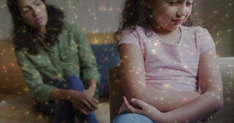 Child folding arms and looking down while parent watches with abstract light overlay