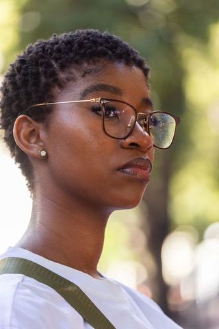 Confident african woman wearing glasses outdoors with natural bokeh and sunlit skin