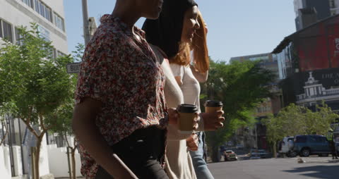 Diverse Friends Strolling in Urban Setting with Coffee
