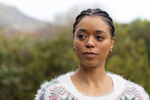African american woman looking sideways in park wearing cozy chevron sweater and gold hoops