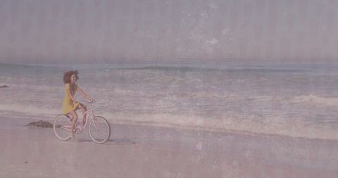 Woman in Yellow Dress Biking Along Tranquil Beachfront