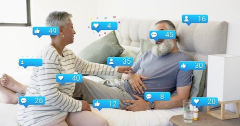 Mature couple receiving social media engagement while bedside caregiving in bedroom