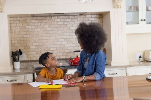 African american mother helping son drawing at kitchen island, cozy family learning