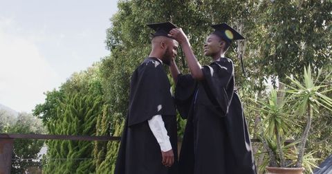 Graduates adjusting caps outdoors in celebration