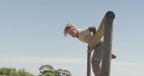 Fit female soldier maneuvering obstacle course outdoors