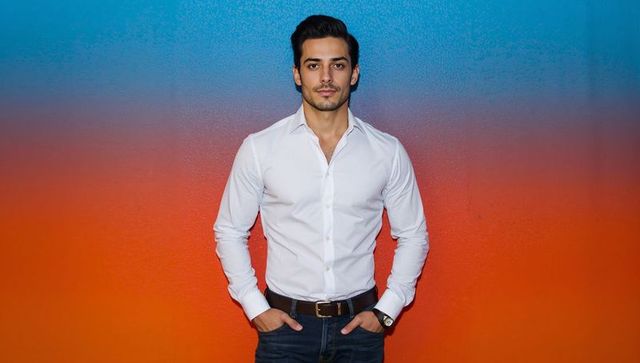 Posing confident man in white shirt and jeans against vibrant blue orange gradient wall