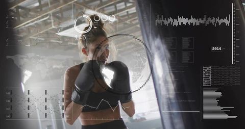 Female boxer training with punching bag and futuristic hud overlay in industrial gym
