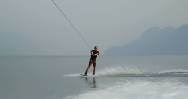 Man Wakeboarding on Misty Lake with Mountain Background - Download Free Stock Images Pikwizard.com