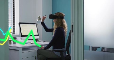 Businesswoman gesturing with vr headset at office desk interacting with virtual data overlay