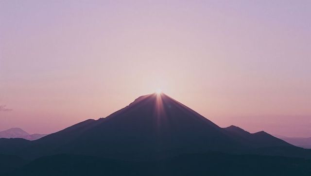 Sunrise Over Mountain Peak with Radiant Sun Rays in Dawn Light