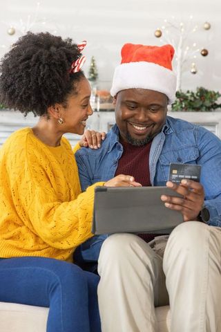 African american couple doing holiday online shopping on tablet with credit card