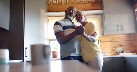 Happy Senior Couple Dancing in Sunlit Kitchen