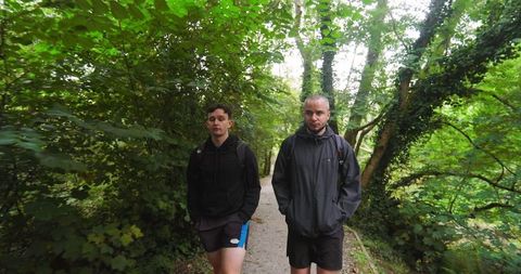 Two men walking on forest trail in athletic gear