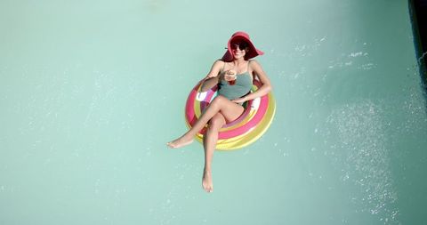 Woman Relaxing on Float Enjoying Drink in Sunlit Pool