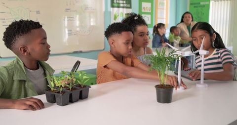 Elementary students learning about renewable energy with wind turbine models and seedlings