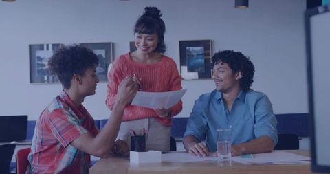 Creative Team Collaborating Over Documents Around Casual Office Table During Brainstorming