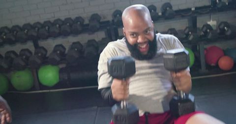 African american man lifting heavy dumbbells with spotter encouraging intense workout