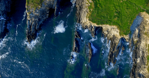 transparent waves crashing against steep cliffs from aerial view - Download Free Stock Videos Pikwizard.com