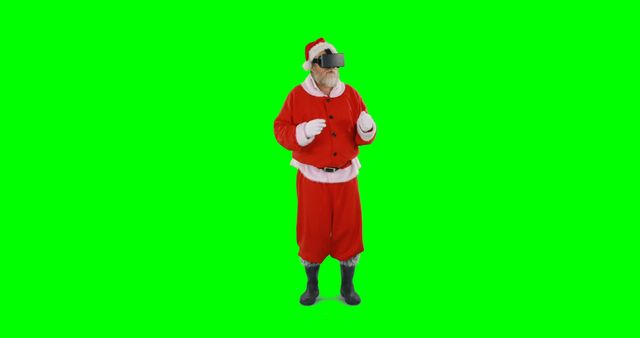 A Caucasian senior man dressed as Santa Claus is wearing virtual reality goggles, with copy space. His stance suggests amazement or engagement with the virtual environment he's experiencing.
