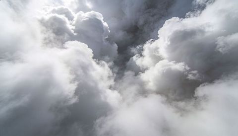 Towering cumulonimbus clouds rising, showing sunlit tops and dark turbulent cores overhead