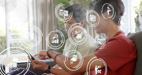 Father and Teen Son Learning Mobile Finance and Analytics on Sofa with Floating UI Icons