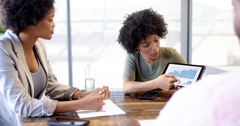 Diverse Team Analyzing Business Data on Tablet in Modern Office
