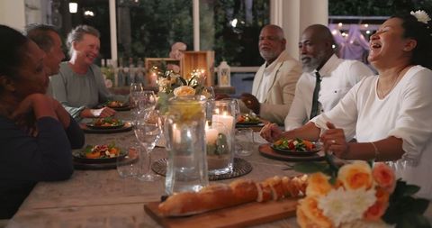 Diverse seniors sharing joy at festive backyard dinner party