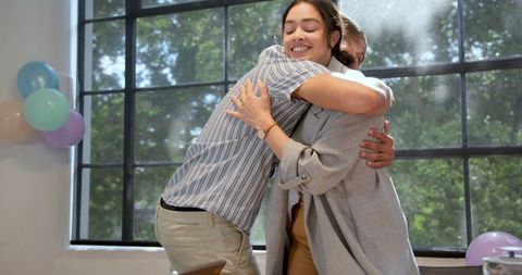 Smiling colleagues celebrating office birthday with hug