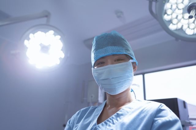 Front view of female surgeon with surgical mask looking at camera in operation room at hospital