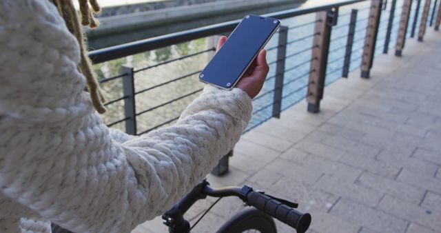 Person Holding Smartphone While Walking Next to Bicycle on Waterfront - Download Free Stock Images Pikwizard.com