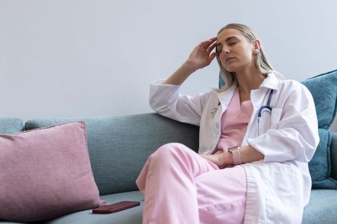 Female clinician resting on sofa after long shift conveying fatigue and calm