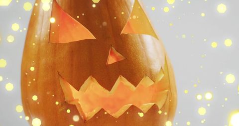 Close-up Carved Jack-o'-Lantern Emitting Warm Glow with Golden Bokeh Lights