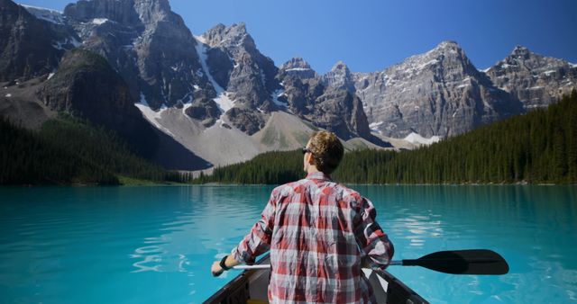 Man Canoeing on Pristine Mountain Lake Amidst Rocky Mountains - Download Free Stock Images Pikwizard.com